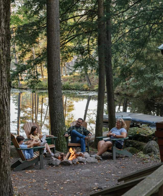 Family sitting around a fire at Hide-a-way Waterfront Cottages