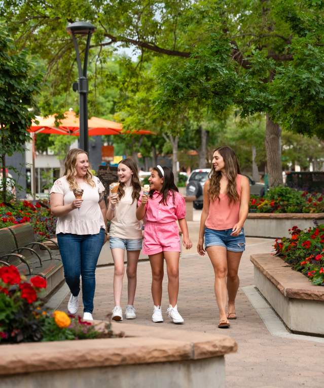 A family eats ice cream as they walk through Old Town Square in the summer