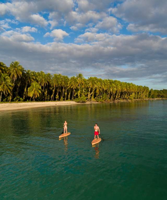 Couple paddling (SUP) on a paradisiac beach at Bocas del Toro Province
