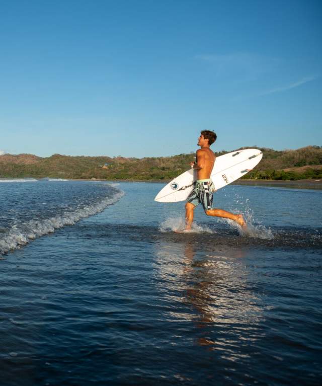 A man with surf board running to Venao beach, Los Santos Province, Panamá