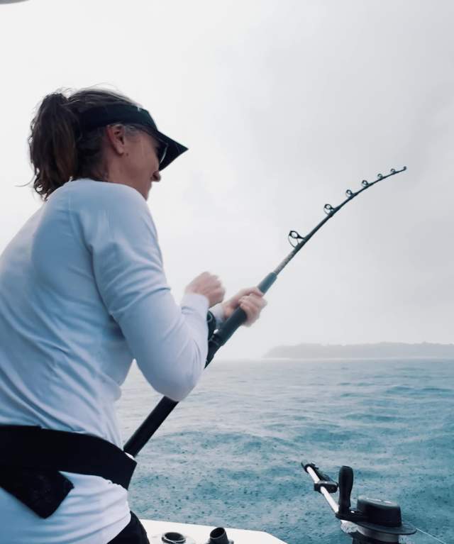 Woman fishing with a rod on a cloudy day in the waters of the Pearl Islands archipelago in Panama City.