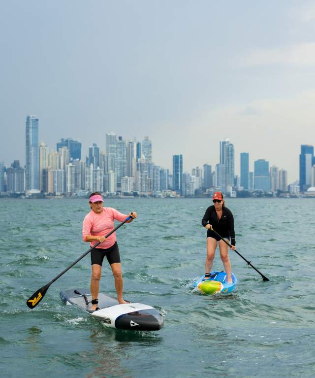 Two woman doing paddle near Taboga Island with Panama City skyline as background