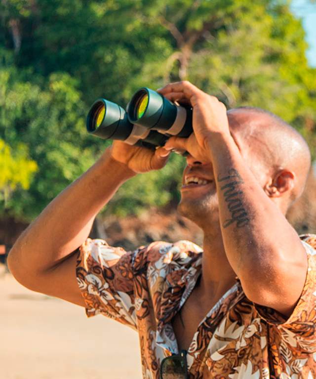 A party of people with cameras is on a beach exploration journey.