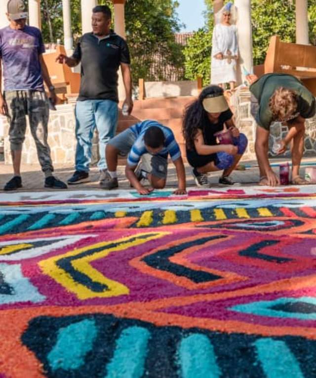 Personas elaborando un tapiz artesanal colorido en el suelo al aire libre en Pedasí, Panamá