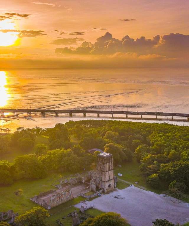 Aerial View of the Cathedral of Our Lady of the Assumption of Panama Viejo. Marine stretch of Cinta Costera in the background. At sunset.