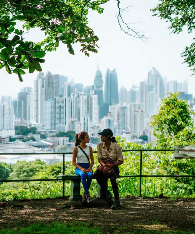 Dos mujeres sentadas disfrutando de la vista panorámica de la Ciudad de Panamá desde un mirador del Parque Natural Metropolitano