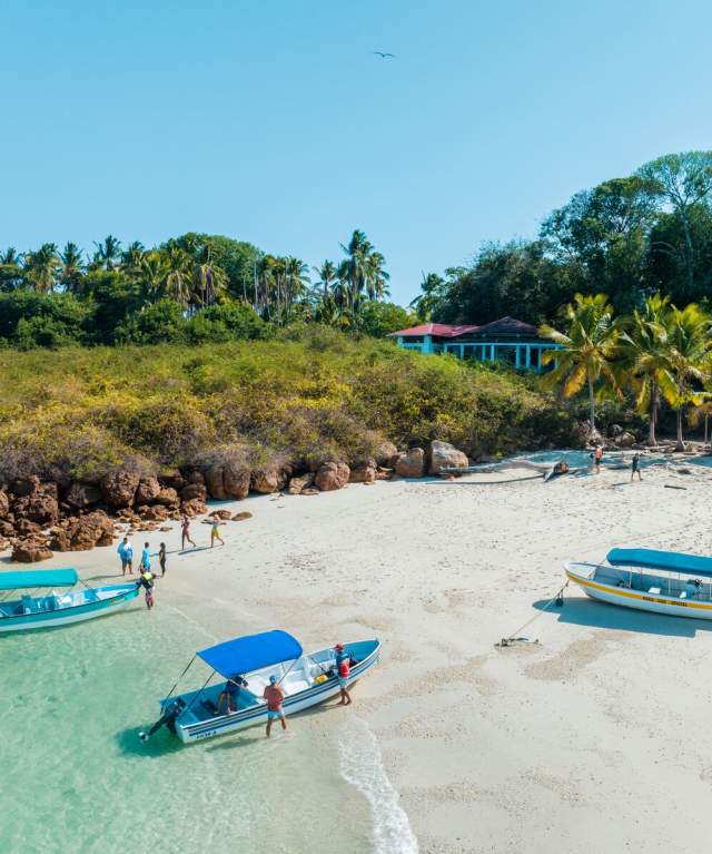 People congregated close to the waterfront of the beach with boats