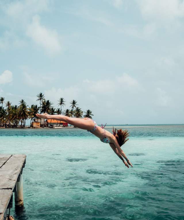 Mujer saltando al agua desde un muelle en la bahía de San Blas, Gunayala, Panamá.