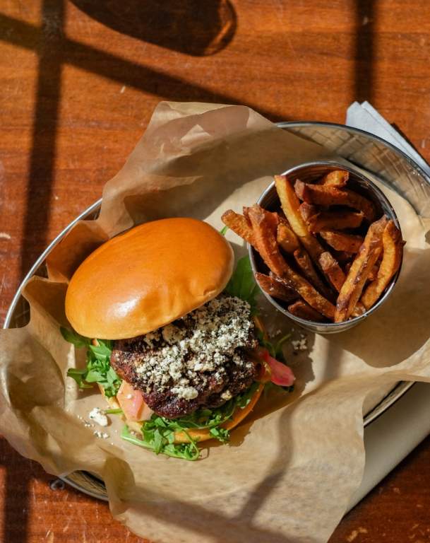 an open faced burger with blue cheese and a cup of french fries