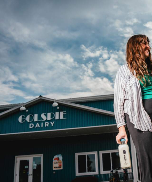 Visitors leaving Golspie Dairy with glass bottle of milk in hand