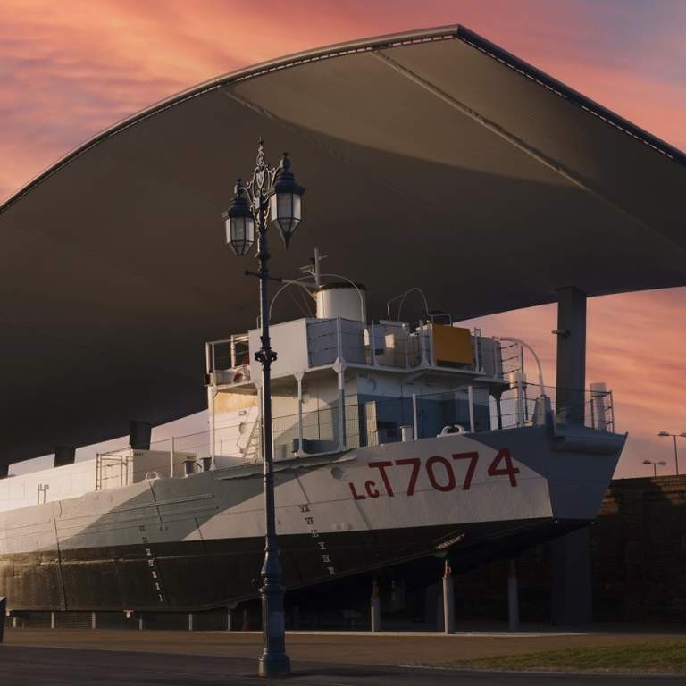 Photograph of LCT 7074 outside The D-Day Story, under a vibrant pink sky