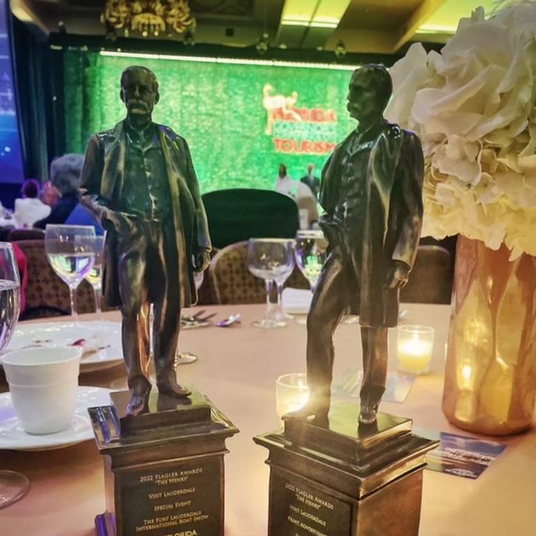 Two Henry Awards displayed on a banquet table. They awards look like miniature statues of Henry Flagler.