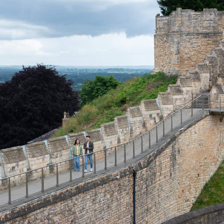 A couple walking along the Medieval Wall Walk at Lincoln Castle