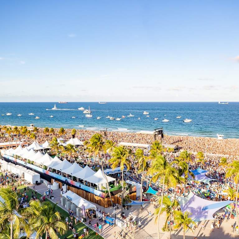Aerial photo of crowds of listeners on Fort Lauderdale Beach with boats anchored in the waters off-shore