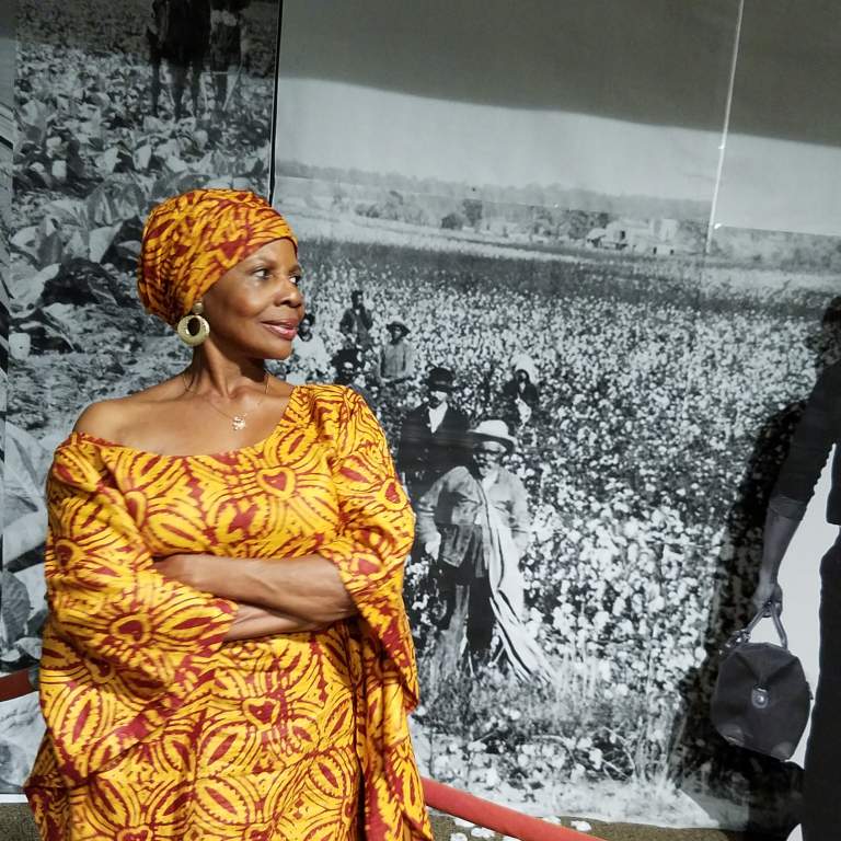 Dr. Kitty Oliver standing in front of a black and white photo at the African American Research Library