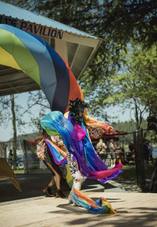 Masked dancer dressed in the rainbow dancing.