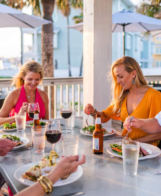 Five people sit at an outdoor table enjoying their dinner.