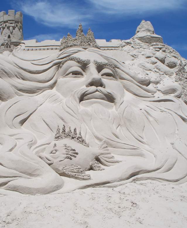 Sand sculpture depicting the face of a large sea king with fish detailing