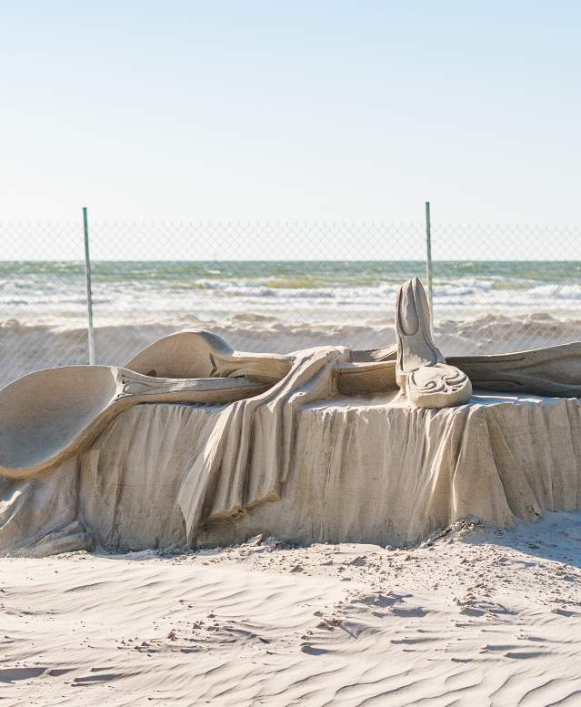 A sand sculpture that is short and long that looks like two spoons in a bed