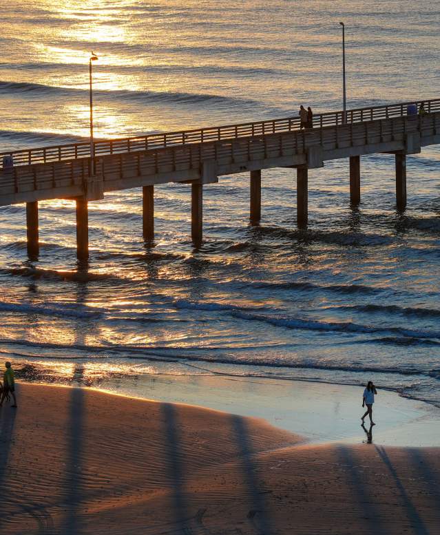 Overhead view of a couple and a single person walking on the beach by Horace Caldwell Pier