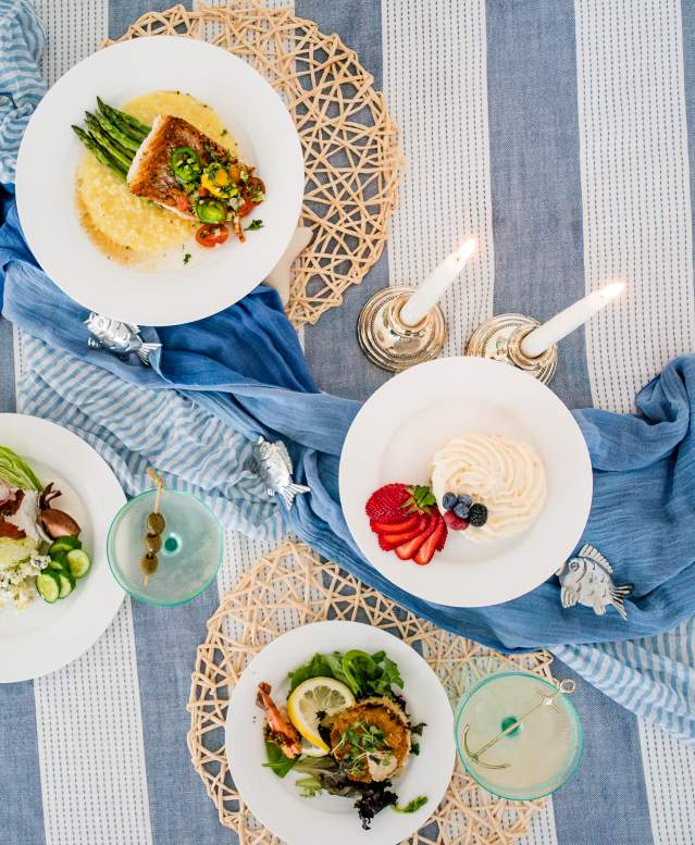 Overhead of a table full of dishes and a coastal place setting.