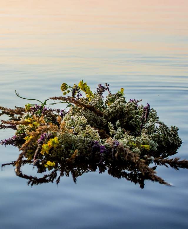A wildflower wreath floats in a serene sea