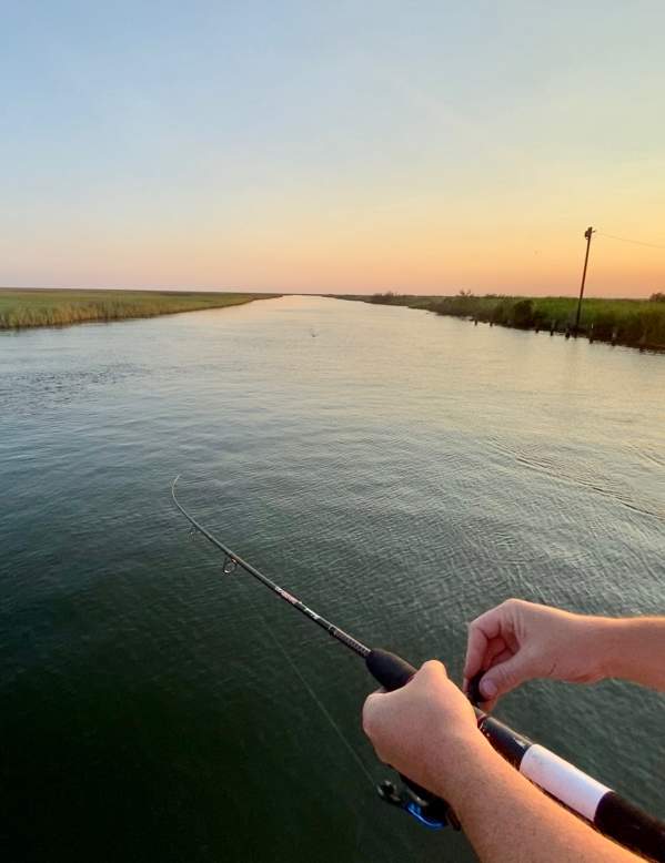 Person holding a fishing pole at sunset in Beaumont