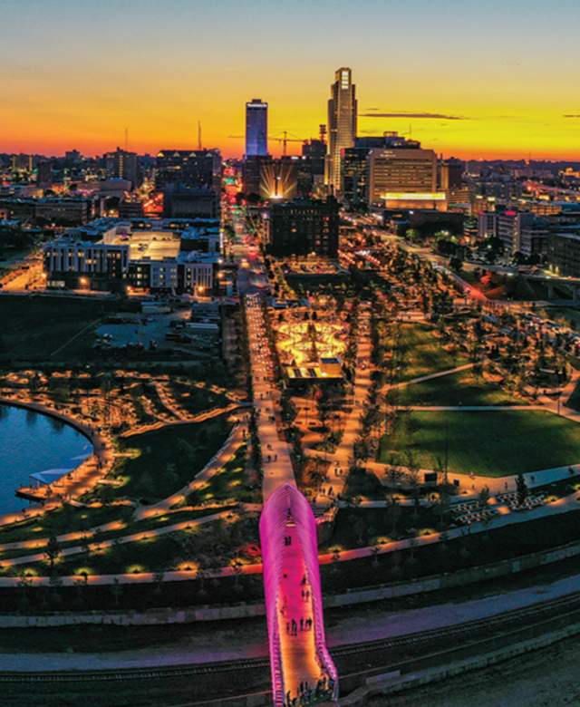 A vibrant sunset skyline shot of Omaha, Nebraska showing pink lights from Heartland of America Park and Farnam Pier.