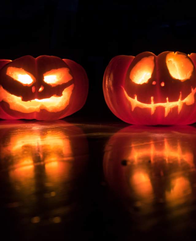Two carved jack-o-lanterns glow on a black background