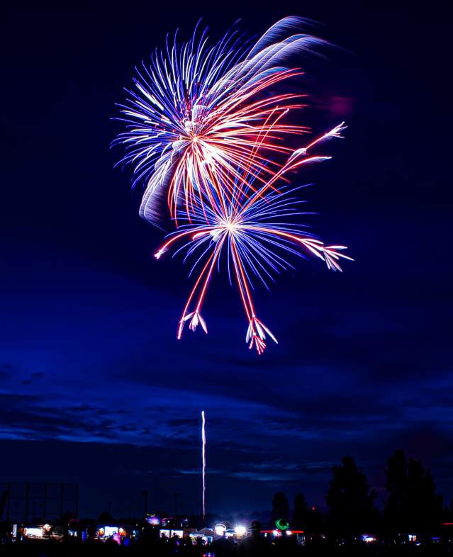 Red and blue fireworks in the dark blue sky during the 4th of July celebration