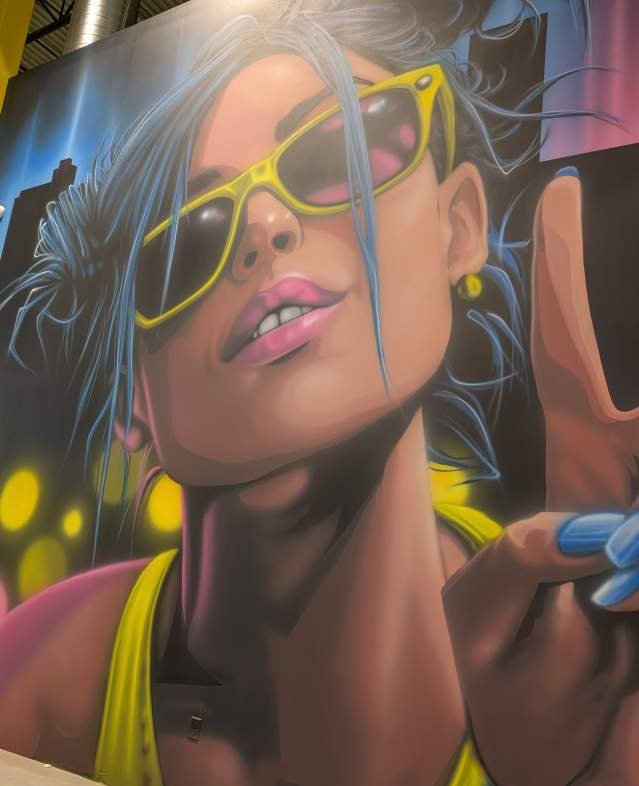 Colorful mural of young adult flashing a peace sign on wall of Slick City Action Park facility.