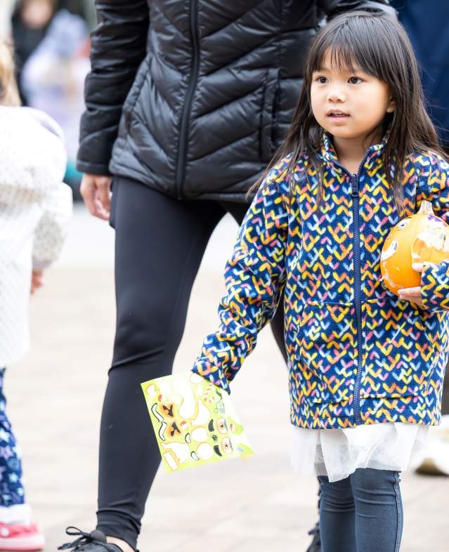 Children carrying pumpkins at Woodbury Lakes' Harvest Hop event.