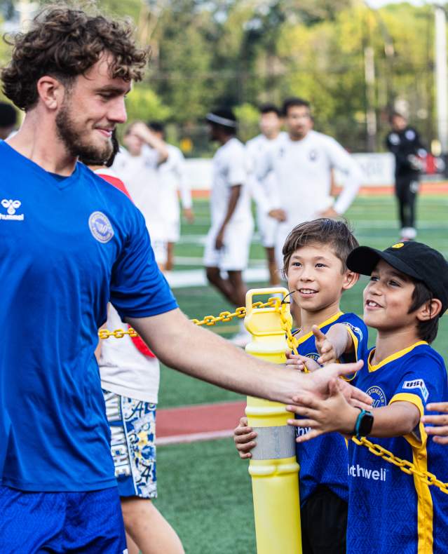A Westchester Soccer Club player greets some fans during a game.