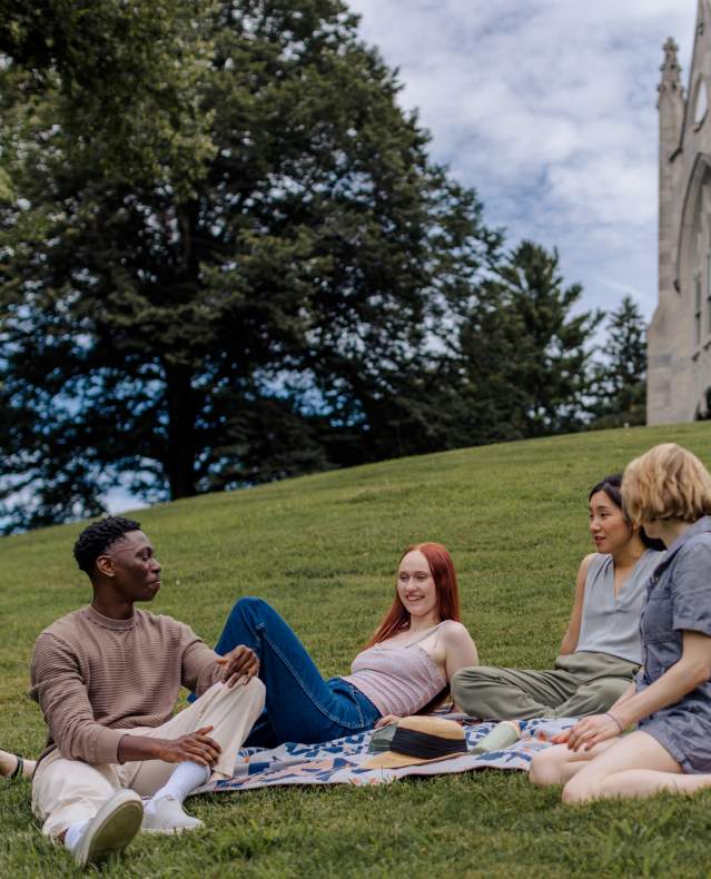 A group of young adults relax on the lawn of Lyndhurst, enjoying a picnic.