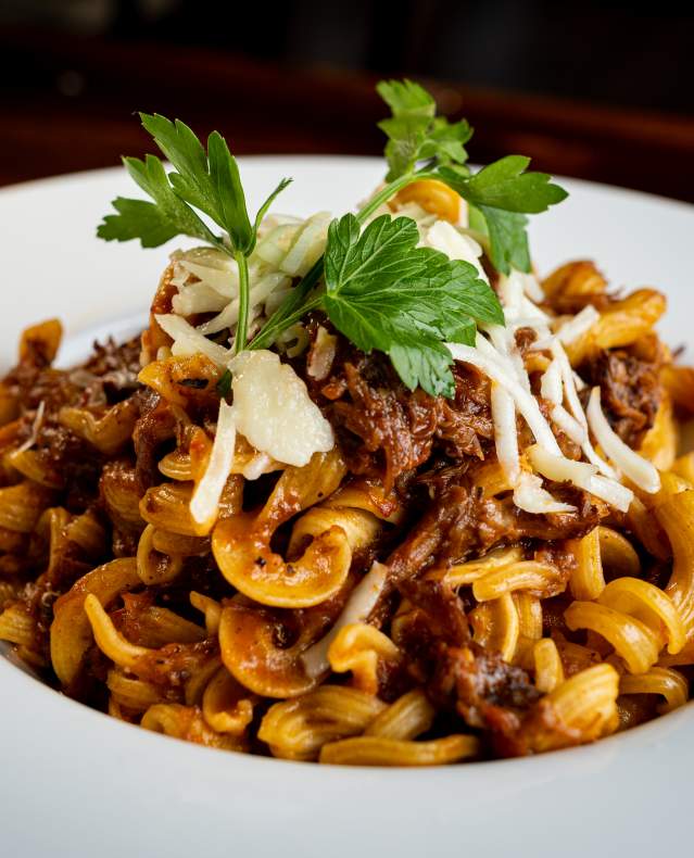 A pasta dish served in a white bowl and garnished with parsley.