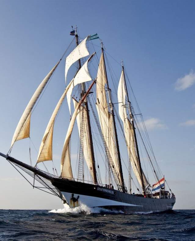The Dutch Tall Ship, Oosterschelde, glides along the open water on a sunny day.