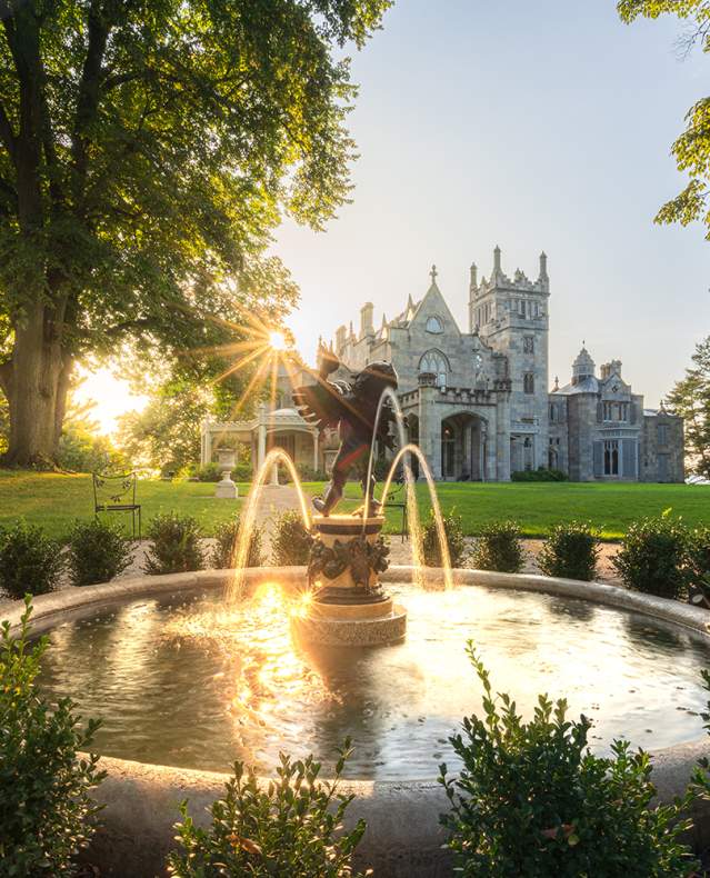 The sun sets over the Hudson River behind Lyndhurst Mansion.