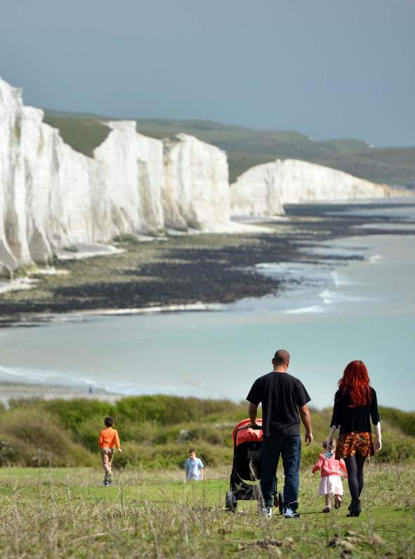 Family walking along coastal path at Seven Sisters, with a view of the sea and white cliffs
