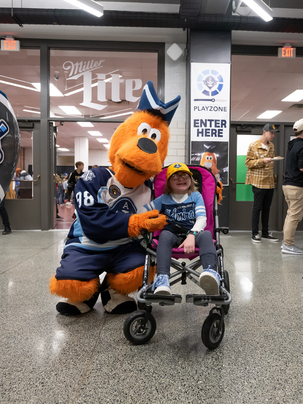 The Milwaukee Admirals mascot, Roscoe, with a young fan in a wheelchair.