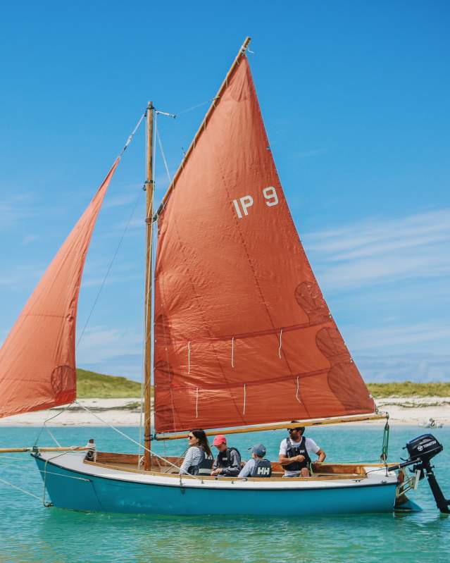 Family on a sailboat with red sail
