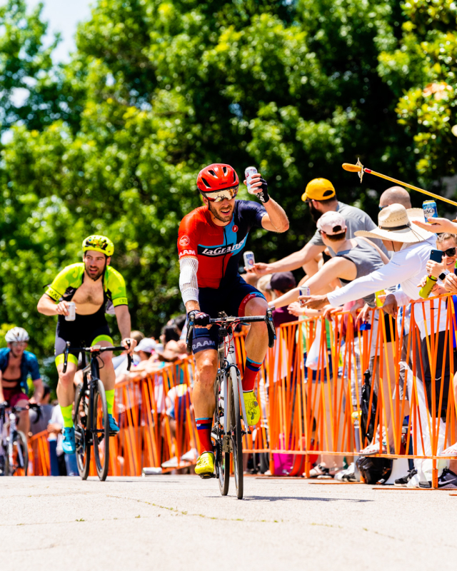 Cyclists biking the Tulsa Tough race with onlookers offering beer and snacks from afar