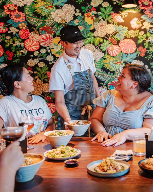 Chef Jeff Chanchaleune serves a table of customers plates of food at his restaurant, Bar Sen