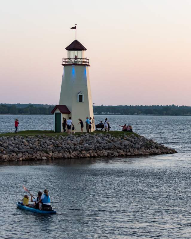 Groups of people sailing and kayaking around the Lake Hefner Lighthouse