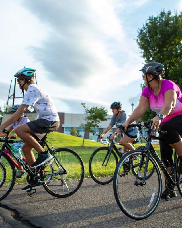 Individuals riding their bikes through a park.