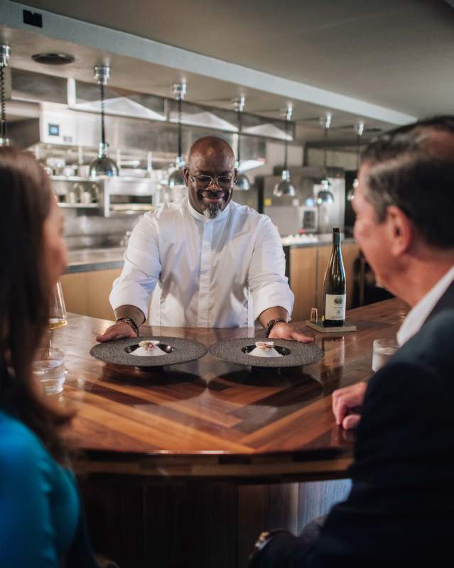Chef Andrew Black serving a plate to patrons at his James Beard Award winning restaurant, Grey Sweater