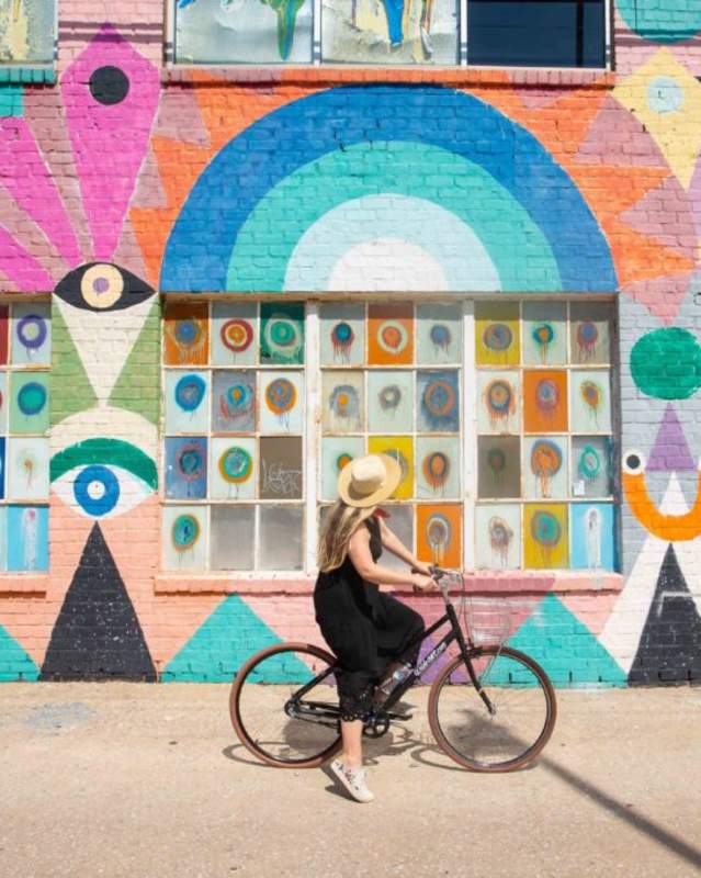 Woman looking at OKC wall mural while riding bicycle