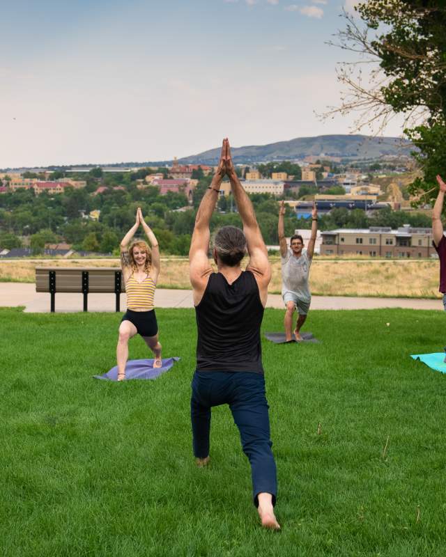 5 people performing a yoga pose in the grass in a Golden park