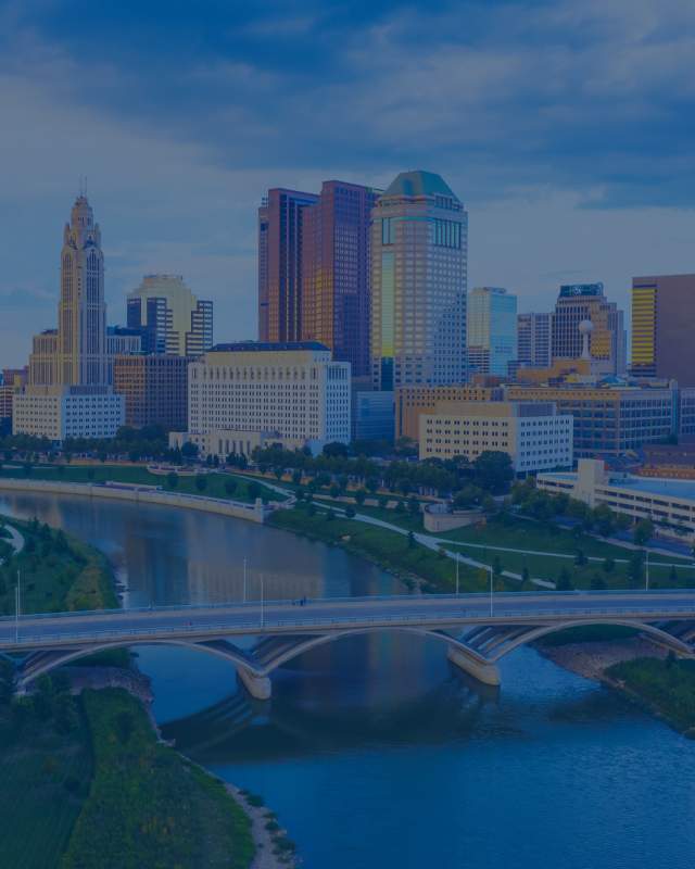 Downtown Columbus, Ohio skyline featuring modern high-rise office buildings and glass towers under a clear sky.