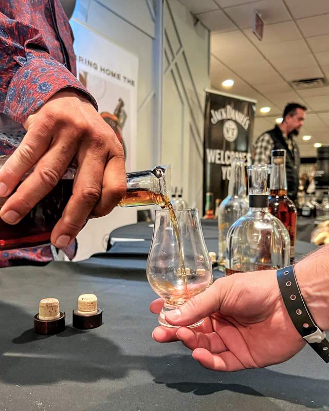 whiskey being poured into a tasting glass at the mountain west whiskey festival in rapid city, sd