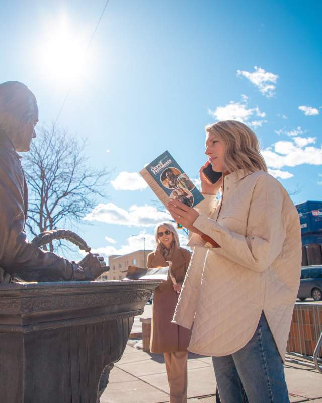 Person listening to the audio tour of city presidents while on phone touring statues in rapid city, sd